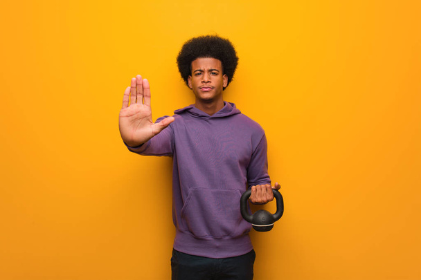 Giovane uomo di fitness africano americano che tiene un manubrio mettendo mano davanti
 - Foto, immagini
