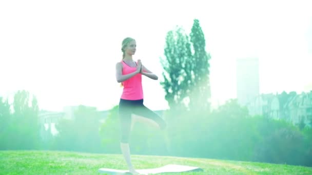 Meisje doet yoga park. Ochtend zonlicht Salute zon staande pose - Video