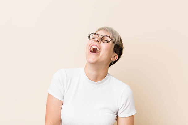 Mujer natural auténtica joven con una camisa blanca relajada y feliz riendo, cuello estirado mostrando los dientes
. - Foto, Imagen