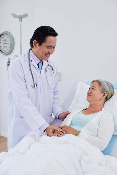 Cheerful doctor talking to recovering senior female patient - Photo, Image