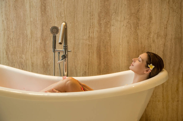 Retrato de uma jovem relaxante na banheira, cuidado orgânico da pele no luxuoso spa do hotel, conceito de bem-estar e autocuidado - Foto, Imagem
