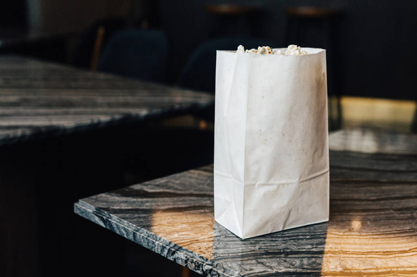 Popcorn al rosmarino in sacchetto di carta sul tavolo in marmo in alto a sinistra con spazio per la copia
. - Foto, immagini
