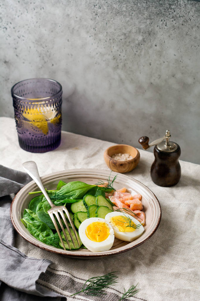 Scandinavian salad with smoked pink salmon, spinach, cucumber and chicken egg in gray ceramic dish.  - Zdjęcie, obraz