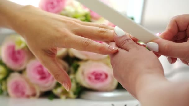 Primer plano de las manos de una manicurista limando las uñas de una joven
 - Metraje, vídeo