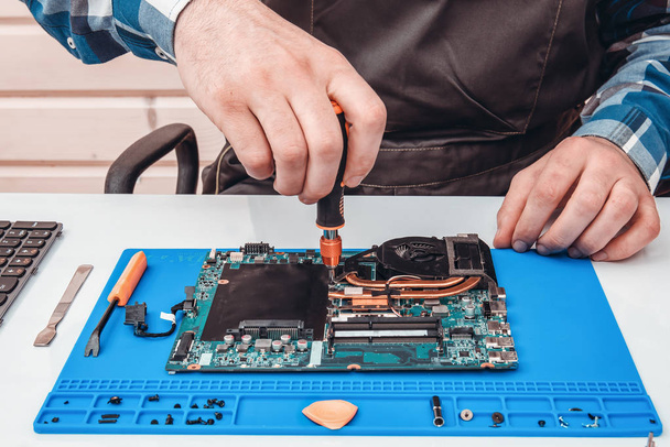 The repairman works in technical support, is engaged in the restoration and cleaning of the laptop. - Foto, afbeelding