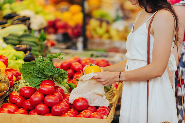 Genç kadın gıda piyasasında pamuk üretmek çanta meyve ve sebze koyar. Alışveriş için yeniden kullanılabilir Eko çanta. Sıfır atık kavramı. - Fotoğraf, Görsel