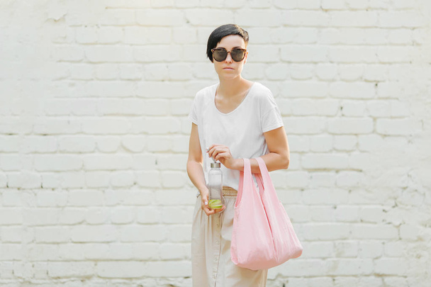 Young woman in  summer clothes with a eco bag and reusable water bottle. Sustainable lifestyle. Eco friendly concept. - Foto, imagen