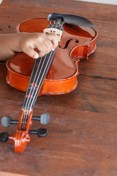 Mano de un niño con un violín poco profundo de campo
 - Foto, Imagen