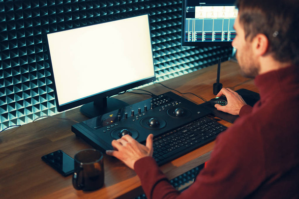 Αρσενικό βιντεογράφο επεξεργάζεται και κόβει πλάνα και ήχο στον προσωπικό του υπολογιστή - Φωτογραφία, εικόνα