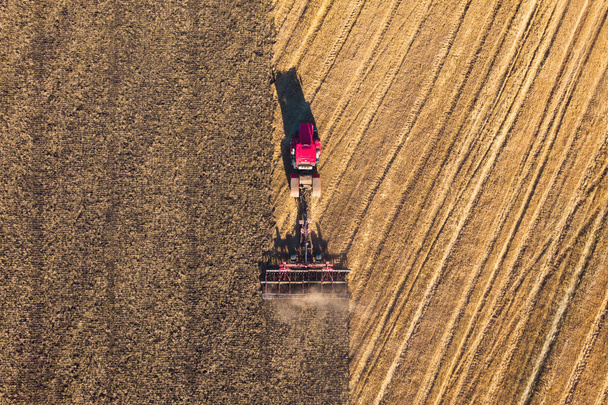 Low altitude aerial top down photo of meadow and farmer in tractor cutting the grass field after this cut grass can dry and be picked up so it can be used as animal fodder for cows. - Photo, Image