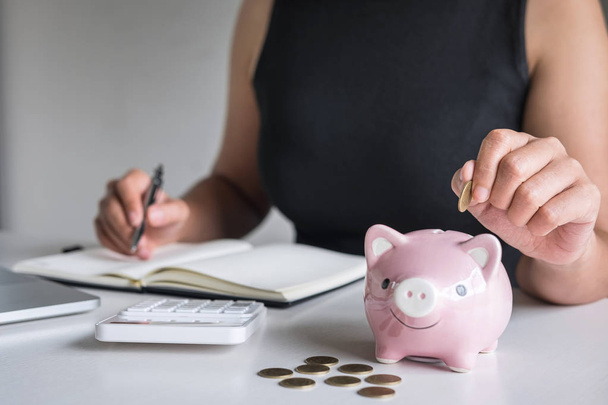 Woman putting golden coin in pink piggy bank for step up growing - Foto, immagini