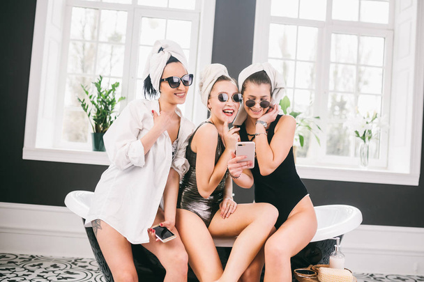 Kép mutatja csoport boldog barátok Spa. lányok a törölközőt a fejüket a szórakozás és a vevő selfie otthon. Barátság, kozmetikai, pizsamás párt fogalmát. Tyúk party a menyasszony a szállodában - Fotó, kép