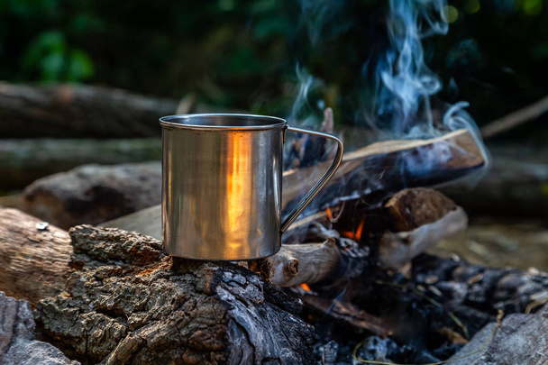 taza de acero en un fuego abierto en la naturaleza. Cocinar en llamas. Camping en
 - Foto, Imagen