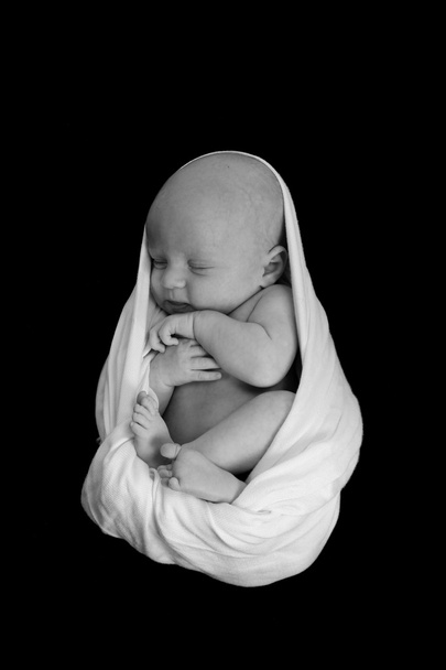 Um bebê recém-nascido envolto em um cobertor dormindo tão
 - Foto, Imagem
