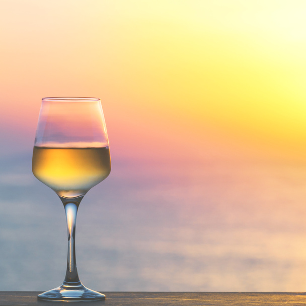 Ποτήρι λευκό κρασί κατά τη δύση του ηλίου. - Φωτογραφία, εικόνα
