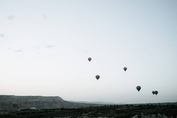 Hot air balloons landing in a mountain Cappadocia Goreme National Park Turkey. - Фото, изображение