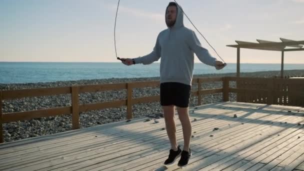 Fáradt ember dobott ugró kötél alatt gyakorolja a tengeri parton a nappali - Felvétel, videó