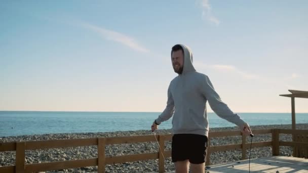 Homem duradouro está pulando perto do mar, girando corda em torno de si mesmo
 - Filmagem, Vídeo