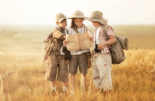 Group of kids travelers read a map at sunset - Photo, Image