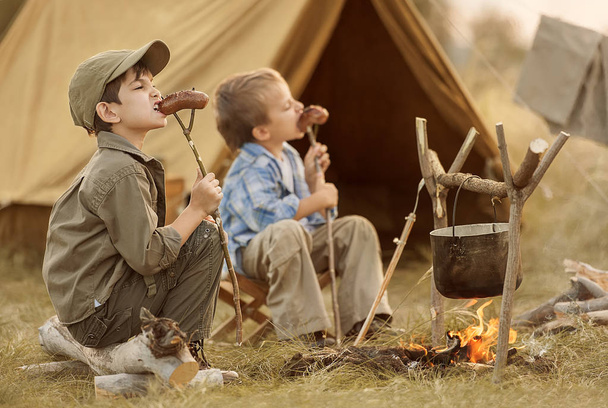 Two of children sitting around the campfire travelers  - Foto, imagen