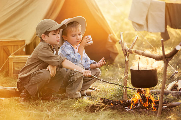 Two of children sitting around the campfire travelers  - Фото, зображення