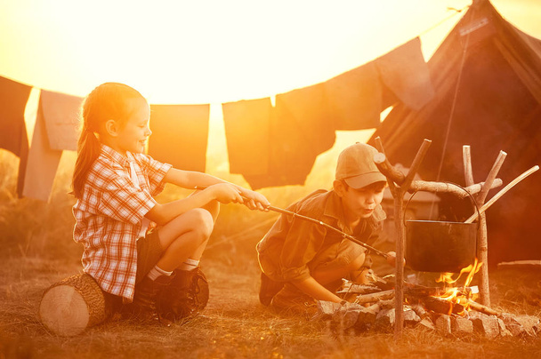 Two of children sitting around the campfire travelers  - Zdjęcie, obraz