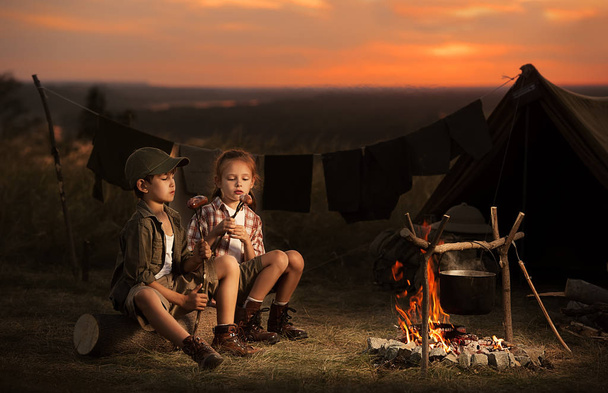 Двоє дітей сидять навколо вогнища мандрівників
  - Фото, зображення