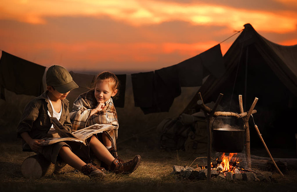 Two of children sitting around the campfire travelers  - Фото, зображення