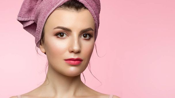 Beauty Woman face with hands. Beautiful Portrait Spa model Girl with Perfect Fresh Clean Skin. Female looking at camera and smiling. Youth and Skin Care Concept. Pink towel on the head, space for text - Фото, зображення