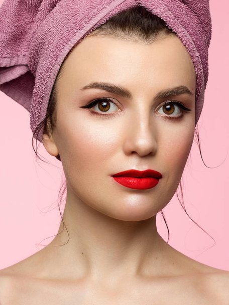 Beauty Woman face with hands. Beautiful Portrait Spa model Girl with Perfect Fresh Clean Skin. Female looking at camera and smiling. Youth and Skin Care Concept. Pink towel on the head, space for text - Foto, Bild