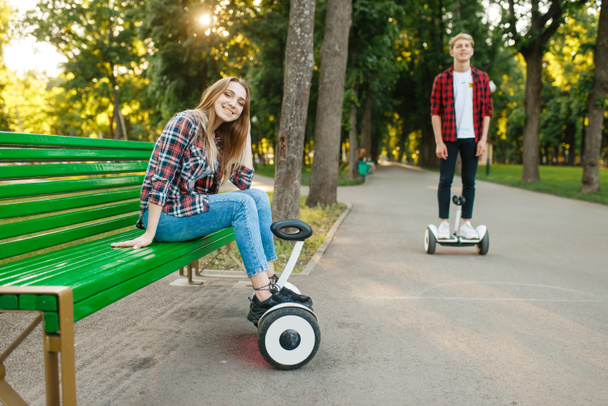 Loisirs de jeune couple avec gyroscope dans le parc d'été. Loisirs de plein air avec gyroboard électrique. Transport avec technologie d'équilibre
 - Photo, image