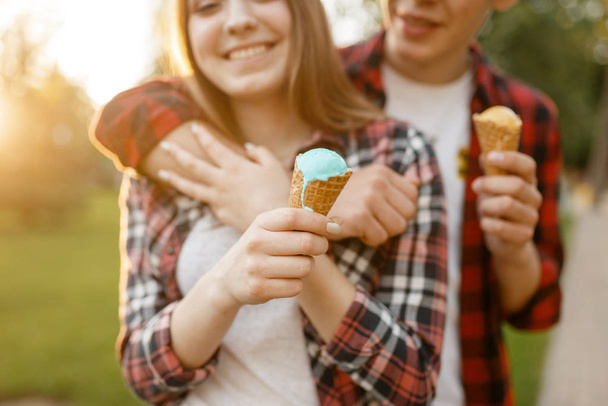 Young love couple with ice cream walking in summer park. Boyfriend and girlfriend leisures with ice-cream, romantic walk - Photo, Image