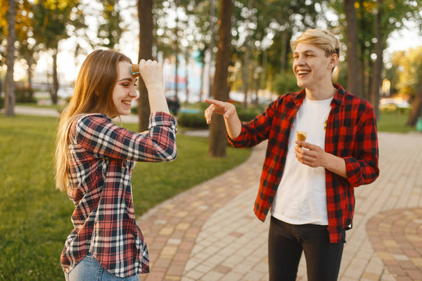 Love couple having fun with ice cream in summer park. Young man and woman leisures with ice-cream, romantic walk together outdoor - Foto, Imagem