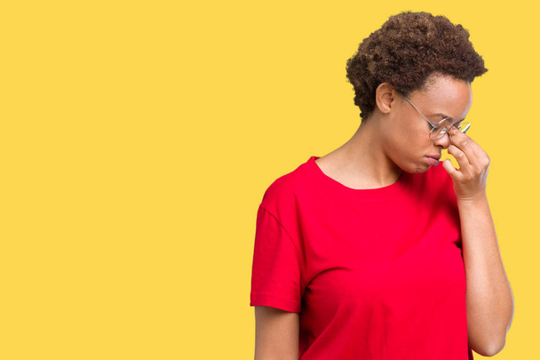 Beautiful young african american woman wearing glasses over isolated background tired rubbing nose and eyes feeling fatigue and headache. Stress and frustration concept. - Photo, Image