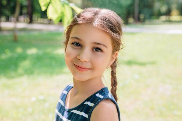 Portrait of adorable smiling little girl with pigtails outdoor in summer day - Фото, изображение