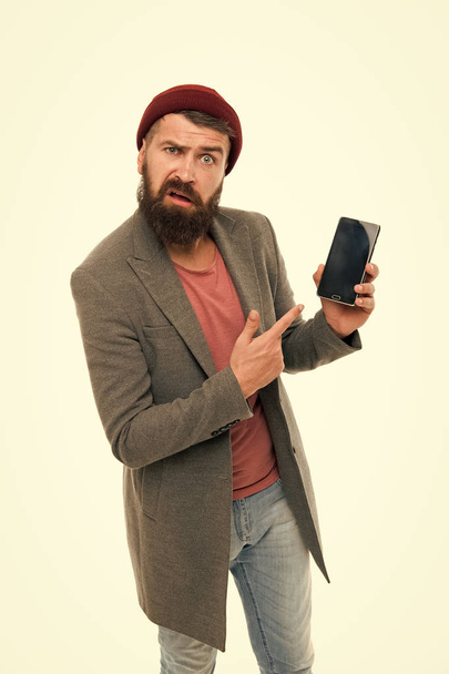 User outraged. Man brutal bully appearance hold smartphone isolated white. Bearded brutal guy pointing at smartphone. Smartphone user outraged mobile application. Client unsatisfied with smartphone - Fotografie, Obrázek