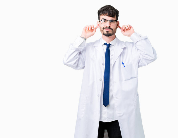 Young professional scientist man wearing white coat over isolated background Smiling pulling ears with fingers, funny gesture. Audition problem - Foto, Imagem