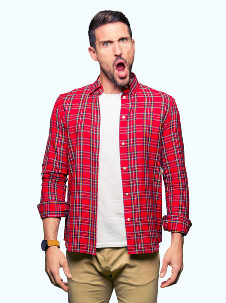 Pohledný muž nosí ležérní tričko v šoku obličeje, skeptický a sarkastický, překvapil s otevřenými ústy - Fotografie, Obrázek