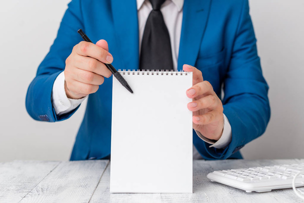 Man holds empty paper with copy space in front of him. Business concept with man in a suite and a tie. White space for advertising message. - Photo, Image