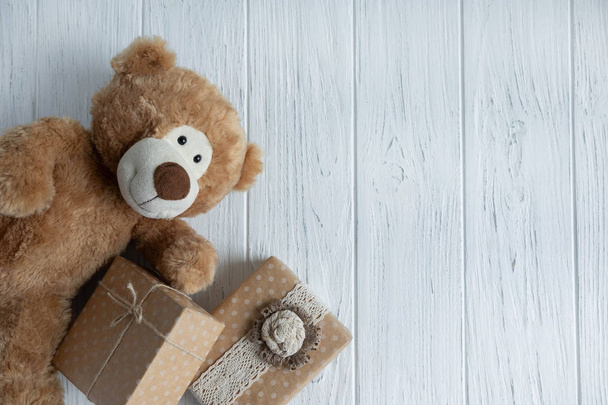 Orso giocattolo, scatole con regali su uno sfondo di legno chiaro. Il design del biglietto di auguri di compleanno. Cornice per il testo dell'iscrizione di congratulazioni con scatole regalo e orsacchiotto
 - Foto, immagini