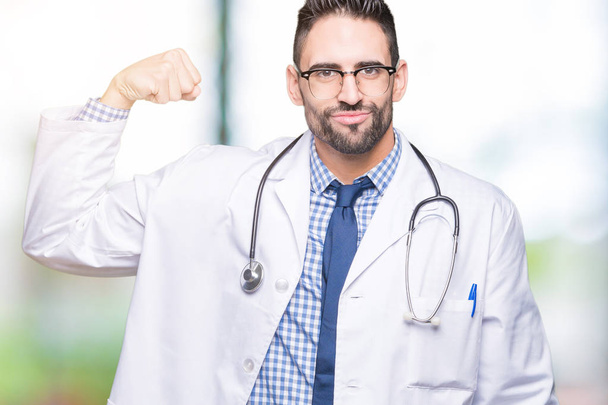 Handsome young doctor man over isolated background Strong person showing arm muscle, confident and proud of power - Photo, image