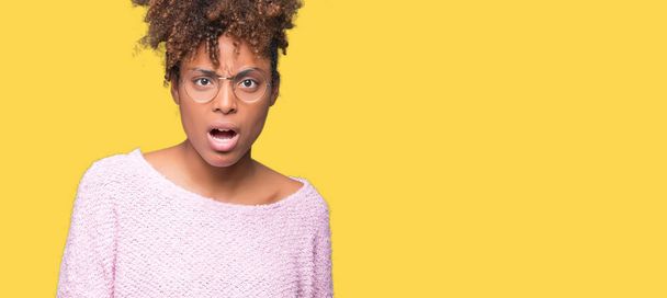 Beautiful young african american woman wearing glasses over isolated background In shock face, looking skeptical and sarcastic, surprised with open mouth - 写真・画像