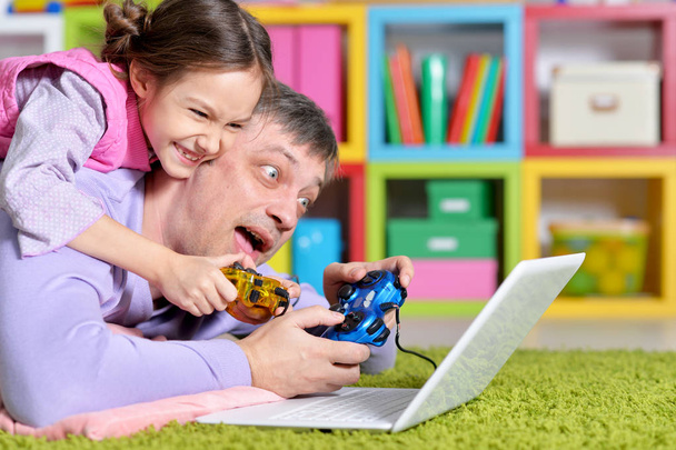 Father with little daughter using  laptop playing game  - Foto, imagen