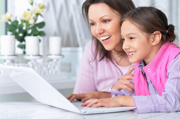happy mother and daughter using laptop together  - Фото, изображение