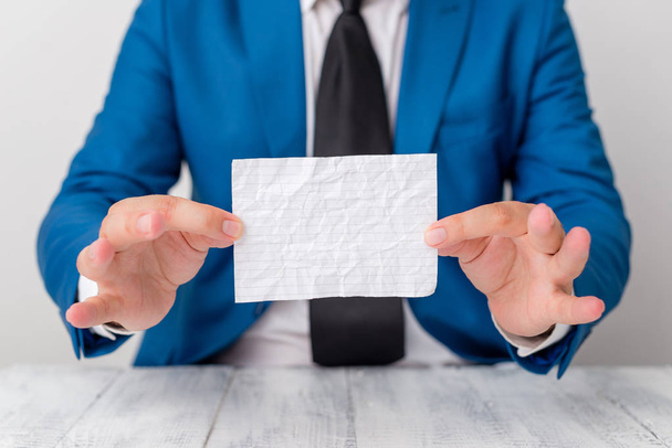 Man holds empty paper with copy space in front of him. Business concept with man in a suite and a tie. White space for advertising message. - Foto, afbeelding