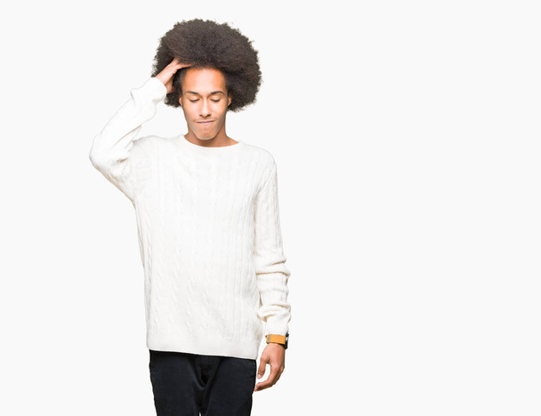 Young african american man with afro hair wearing winter sweater confuse and wonder about question. Uncertain with doubt, thinking with hand on head. Pensive concept. - Foto, Imagem