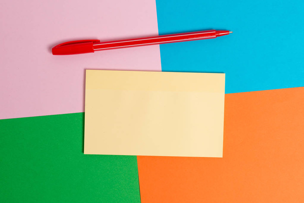 Színes íróasztal különböző méretű és típusú üres papírok, irodai készülékek és tanulmányi kellékek. Táblázat: rózsaszín, kék, zöld és narancssárga négyzetek papír matricával. - Fotó, kép