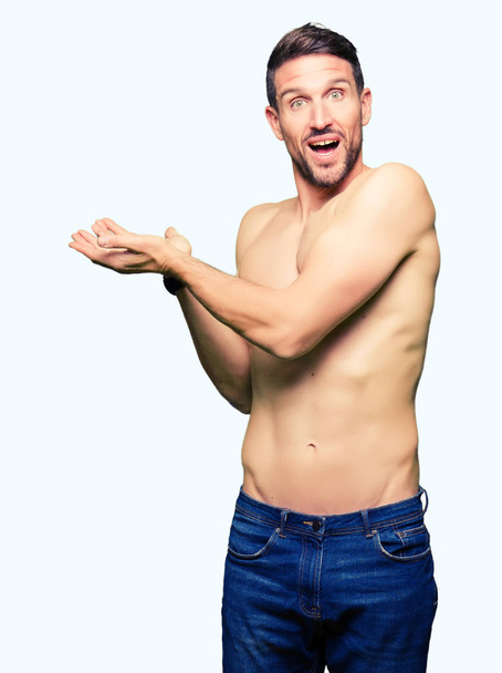 Красивий без сорочки чоловік показує оголені груди Направляючи на бік рукою і відкритою долонею, представляючи рекламу, усміхаючись щасливим і впевненим
 - Фото, зображення