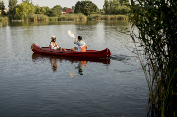 Loving couple rowing on the lake at summer day - Фото, зображення