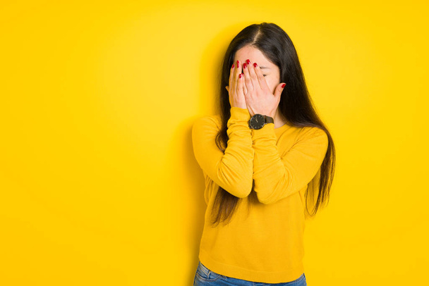 Beautiful brunette woman over yellow isolated background with sad expression covering face with hands while crying. Depression concept. - Fotoğraf, Görsel
